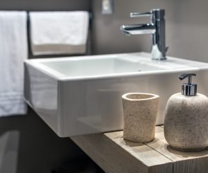 A shallow shot of a modern sink beside the bottle in the bathroom